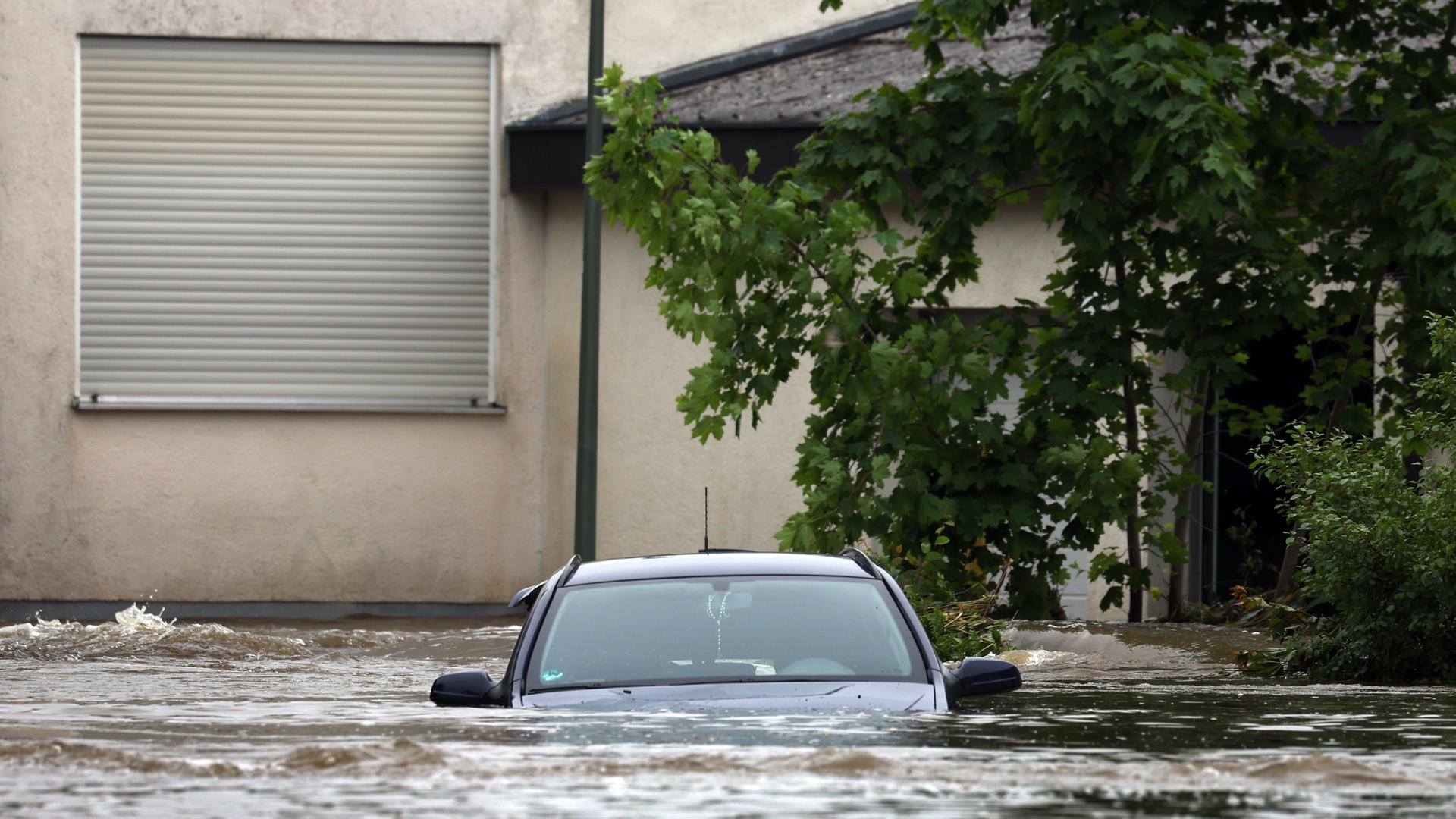 Ein Auto steht vor einem Haus im Hoch-Wasser. 