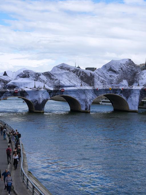 Fußgänger gehen in der Nähe der temporären Kunstinstallation „La Caverne du Pont Neuf“ (Die Höhle des Pont Neuf) auf der Brücke Pont Neuf in Paris.
