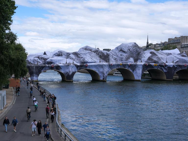 Fußgänger gehen in der Nähe der temporären Kunstinstallation „La Caverne du Pont Neuf“ (Die Höhle des Pont Neuf) auf der Brücke Pont Neuf in Paris.