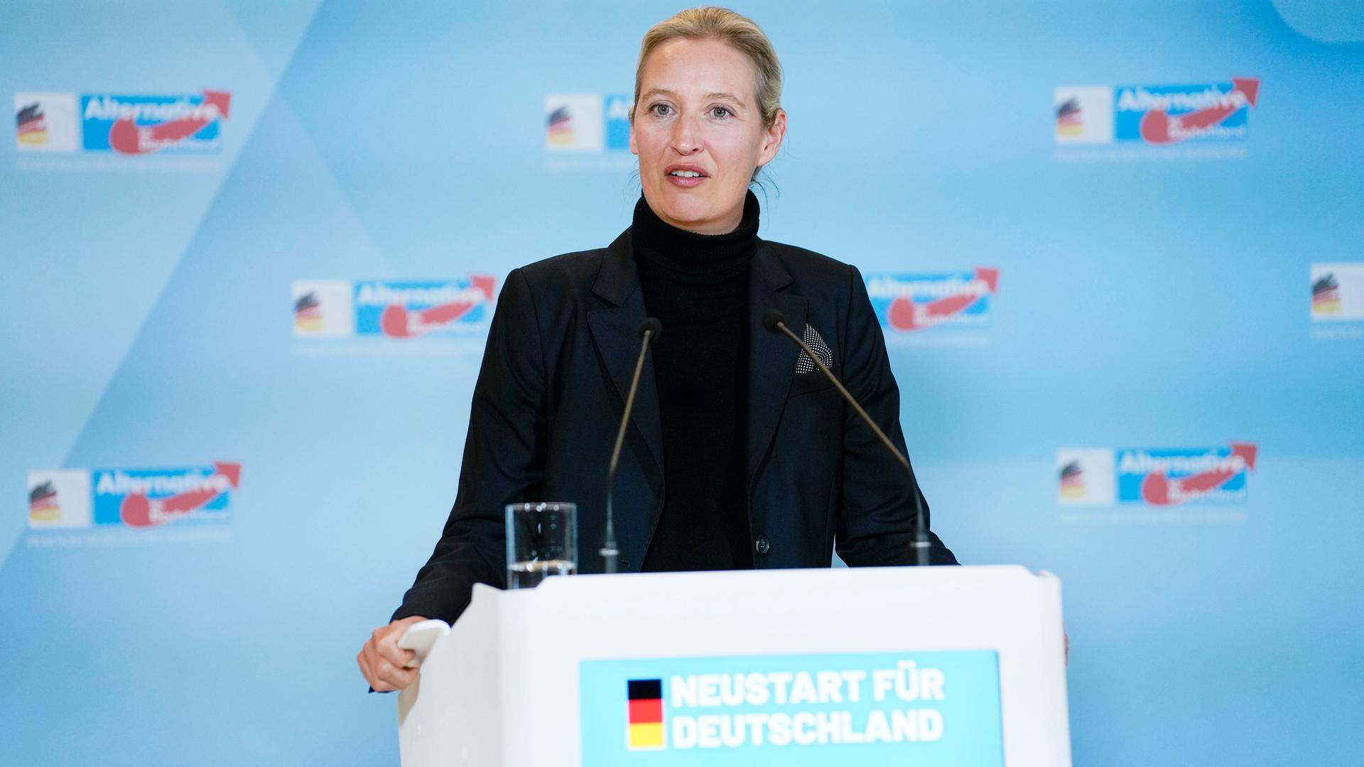 Alice Weidel steht bei einem Pressestatement im Reichstagsgebäude an einem Rednerpult vor hellblauem Hintergrund mit dem Logo der AfD.