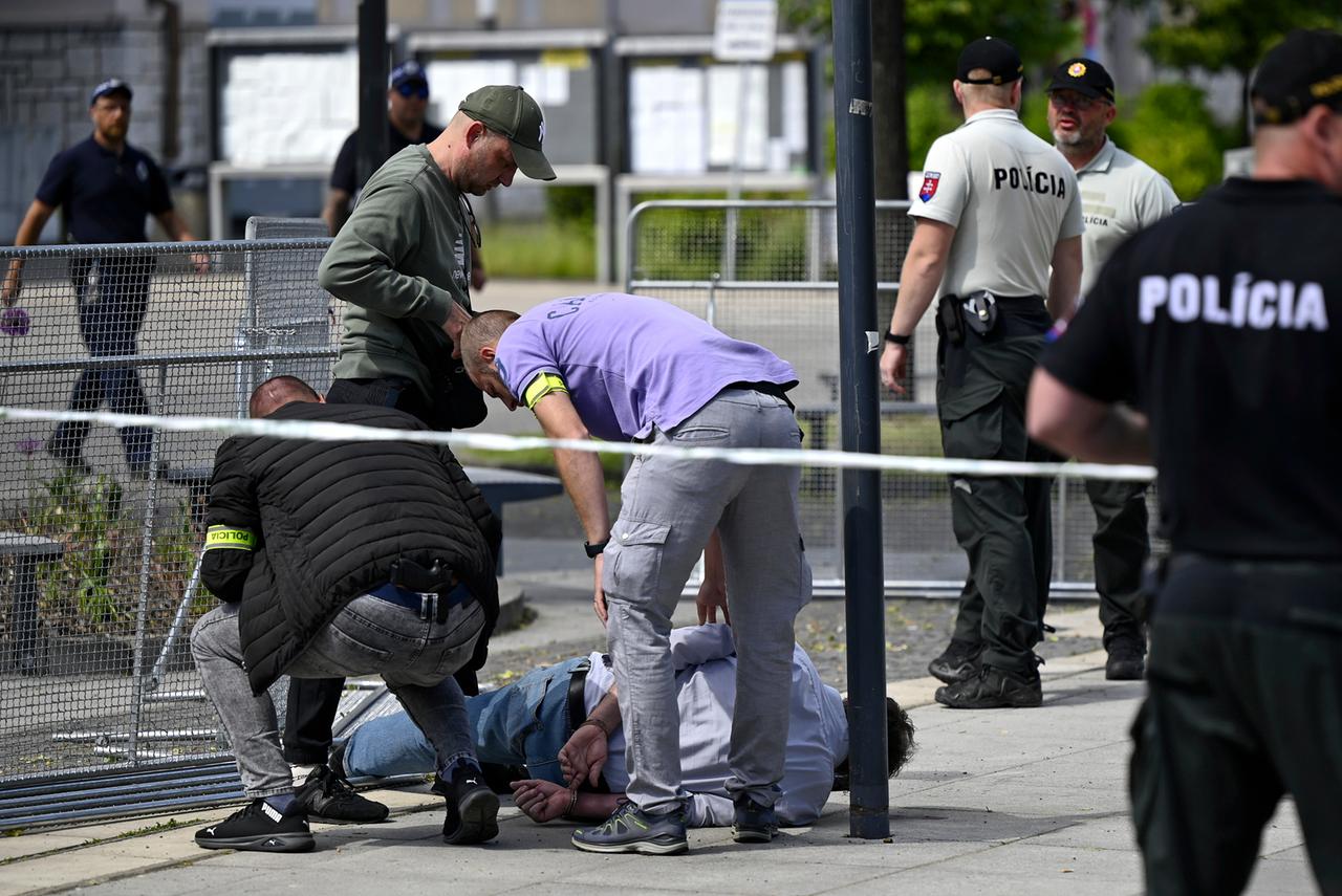 Der Mann liegt mit auf dem Rücken gefesselten Händen seitlich auf einem Bürgersteig. Um ihn herum mehrere uniformierte beziehungsweise in zivil gekleidete Polizisten.