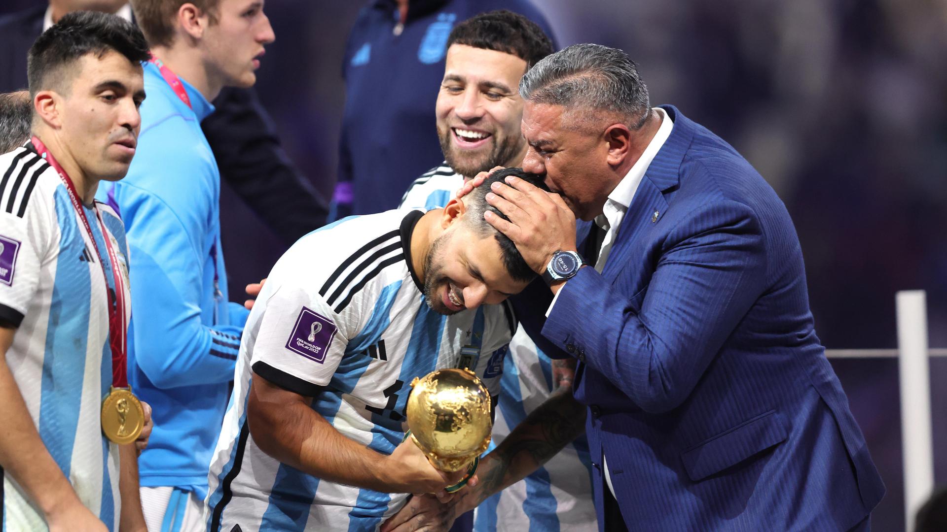 Claudio Tapia, Präsident des Argentinischen Fußballverbands (AFA), küsst Ex-Nationalspieler Sergio Agüero bei der WM-Siegerehrung in Katar auf den Kopf.