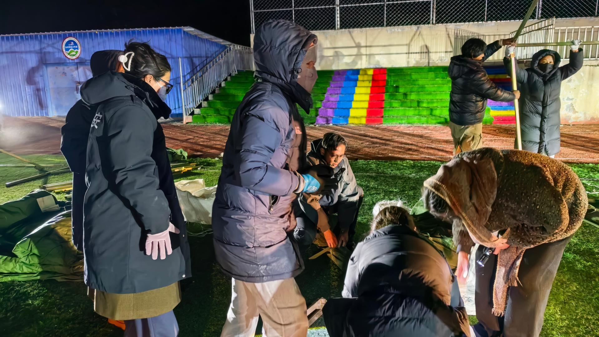 Durch ein Erdbeben in China sind viele Häuser eingestürzt, Menschen bauen Zelte auf einem Schulsportplatz auf. Durch ein Erdbeben in China sind viele Häuser eingestürzt, Menschen bauen Zelte auf einem Schulsportplatz auf.