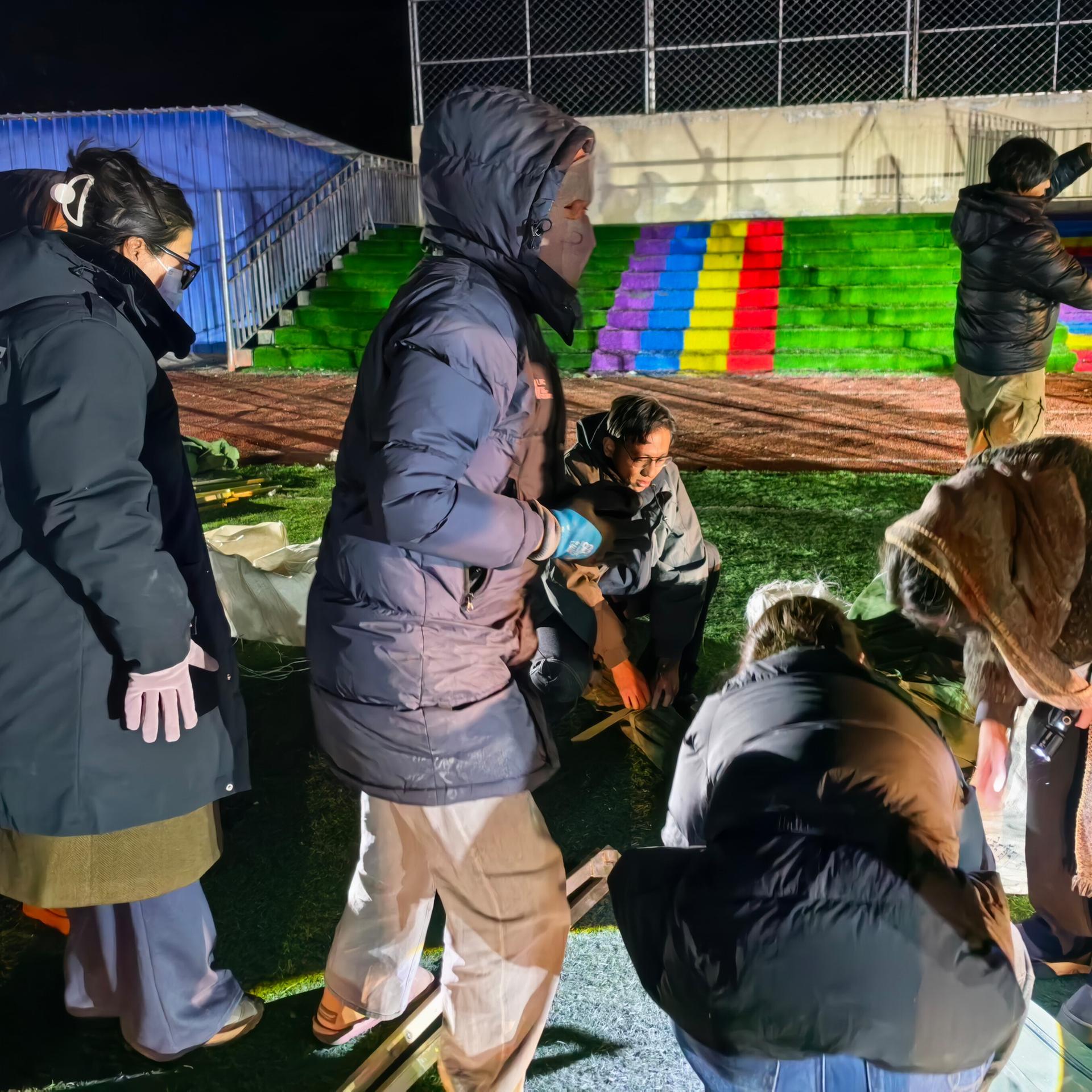 Durch ein Erdbeben in China sind viele Häuser eingestürzt, Menschen bauen Zelte auf einem Schulsportplatz auf.