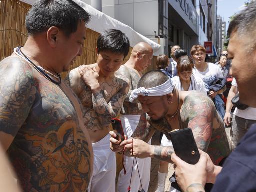 Männer mit Ganzkörpertätowierungen fotografieren ihre Tattoos bei einem Festival in Japan.