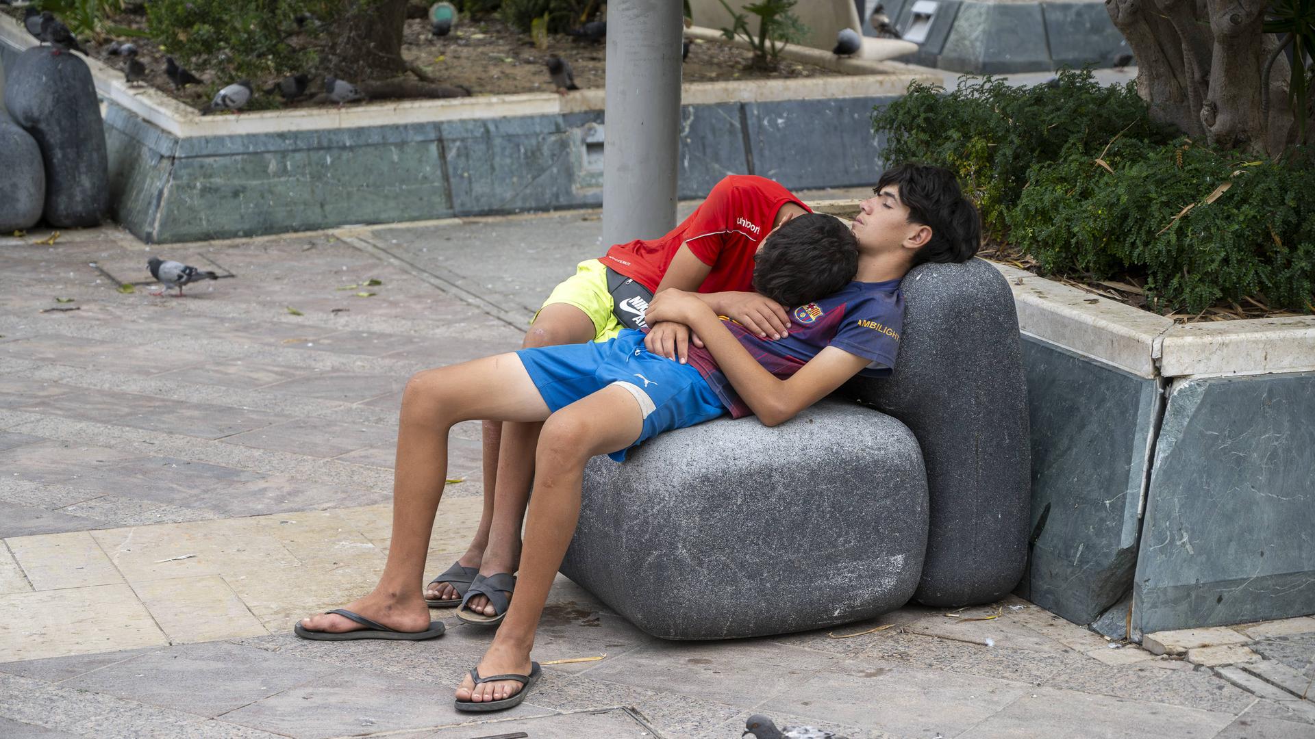 Zwei Kinder schlafen auf einem Stein in Ceuta.