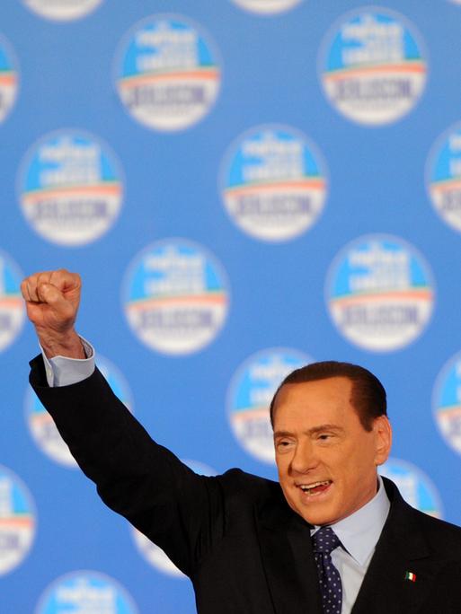 Silvio Berlusconi streckt bei einer Wahlkampfveranstaltung im Februar 2013 auf der Bühne die geballte rechte Faust nach oben.