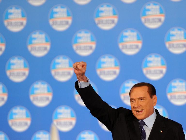 Silvio Berlusconi streckt bei einer Wahlkampfveranstaltung im Februar 2013 auf der Bühne die geballte rechte Faust nach oben.