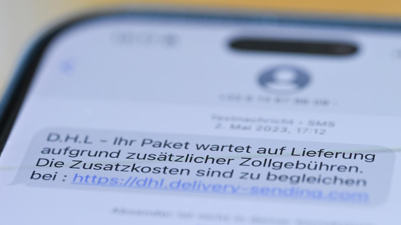 Auf einem Smartphone ist eine Betrugs-SMS zu lesen, in der Kriminelle ein Paket ankündigen und dafür Zollgebühren einfordern. 