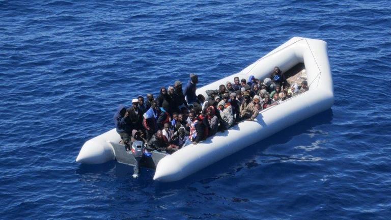 Flüchtlinge sitzen enggedrängt in einem Schlauchboot, das auf dem Mittelmeer treibt.