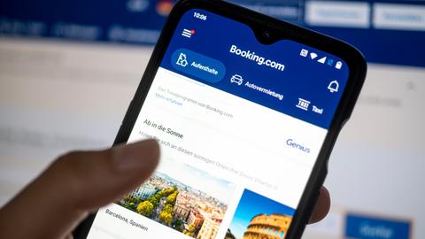 Auf einem Smartphone ist die App des Reiseportals Booking.com zu sehen.