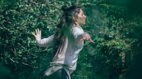 Tanzen - die Spannung zwischen Bei-sich-Sein und Außer-sich-Sein. Zu sehen: Eine Frau tanzt in einem Wald. 