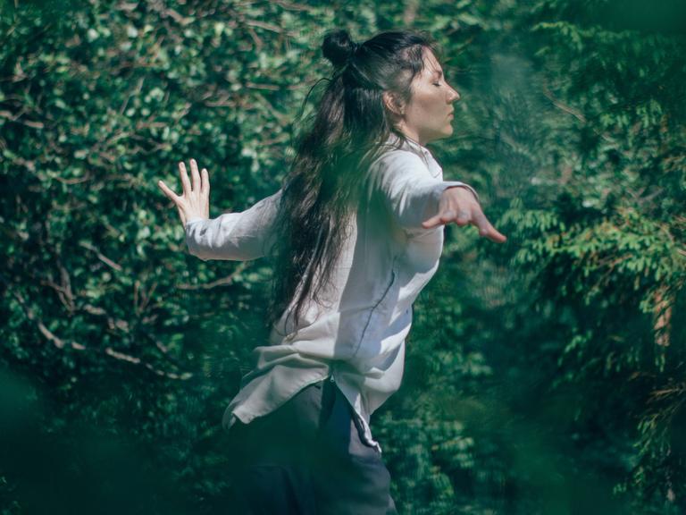 Tanzen - die Spannung zwischen Bei-sich-Sein und Außer-sich-Sein. Zu sehen: Eine Frau tanzt in einem Wald. 