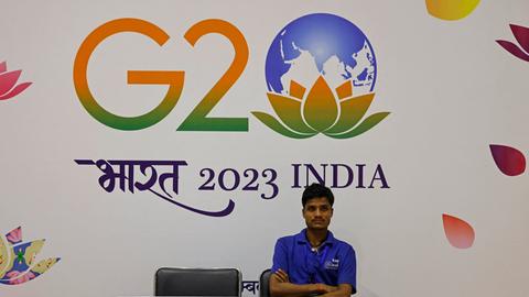 Mann sitzt vor dem G20 Banner in Neu Dehli am 8.9.2023