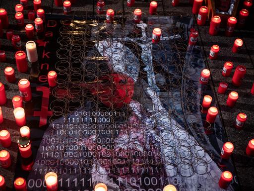 Teilnehmende einer Protestkundgebung haben an einem stilisierten Bild eines Geistlichen Kerzen für die Opfer von sexuellem Missbrauch in der Kirche entzündet.