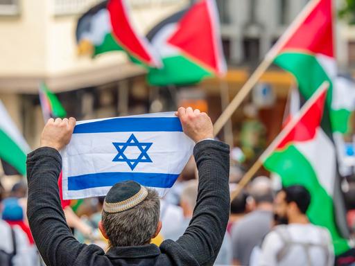 Ein Pro-Israel-Demonstrant hält einer Free-Palestine-Demonstration die israelische Flagge entgegen