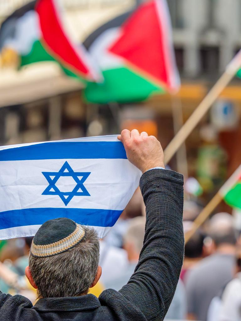 Ein Pro-Israel-Demonstrant hält einer Free-Palestine-Demonstration die israelische Flagge entgegen