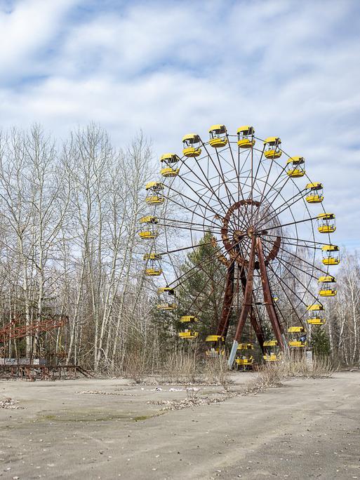 Das verlassene und verfallene Riesenrad von Prypjat vor blauem Himmel mit weißen Wölkchen.