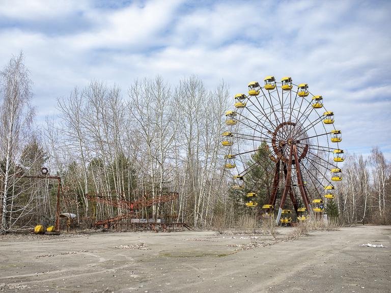 Das verlassene und verfallene Riesenrad von Prypjat vor blauem Himmel mit weißen Wölkchen.
