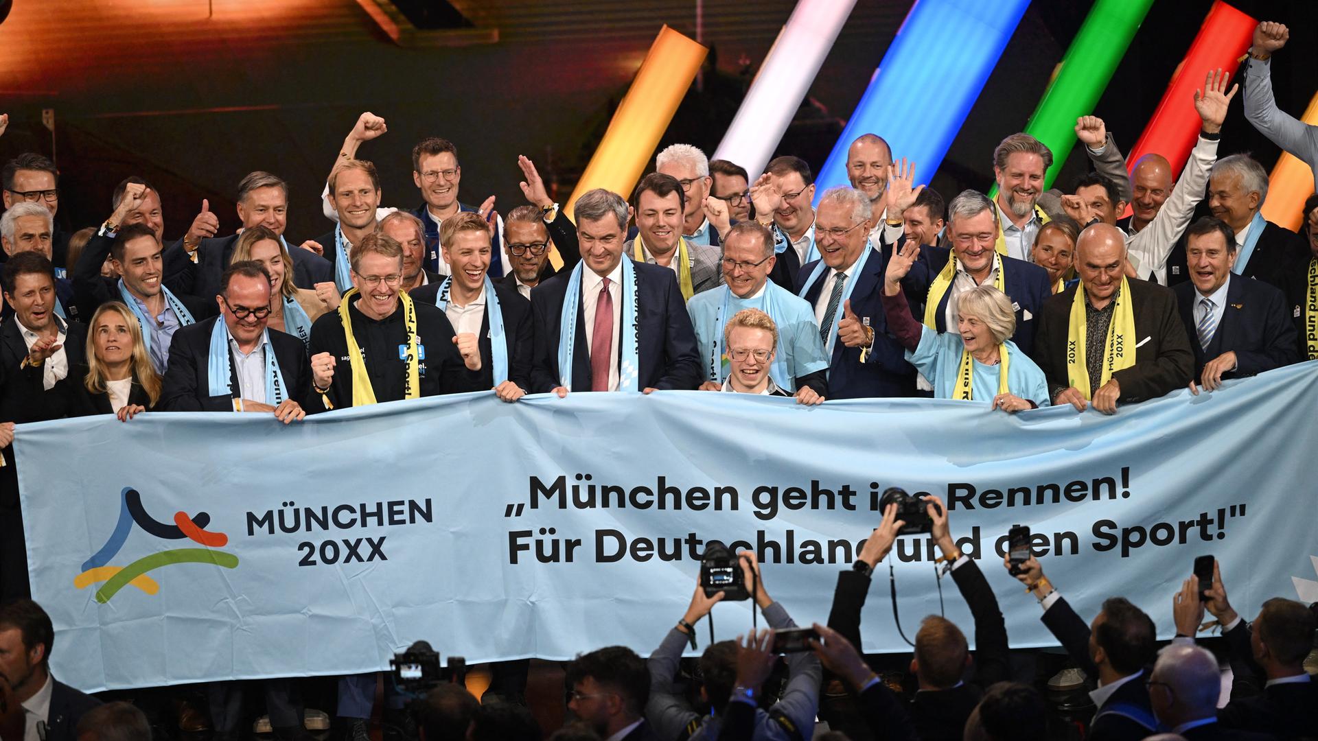 Markus Söder (m.), Ministerpräsident von Bayern, und Dominik Krause (l.), Oberbürgermeister von München, und weitere Mitglieder der Münchner Delegation jubeln nach der Wahl des deutschen Olympia-Bewerbers München für 2036, 2040 oder 2044. Markus Söder (m.), Ministerpräsident von Bayern, und Dominik Krause (l.), Oberbürgermeister von München, und weitere Mitglieder der Münchner Delegation jubeln nach der Wahl des deutschen Olympia-Bewerbers München für 2036, 2040 oder 2044.