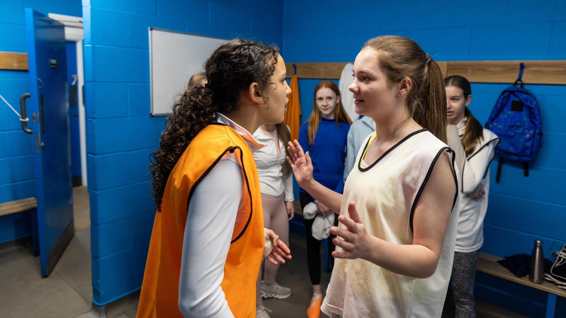 Konfliktlotsin: Mädchen in einer Schulumgebung neben Lockern, es sieht so aus, als hätte es einen Streit gegeben, ein Mädchen versucht, zu schlichten