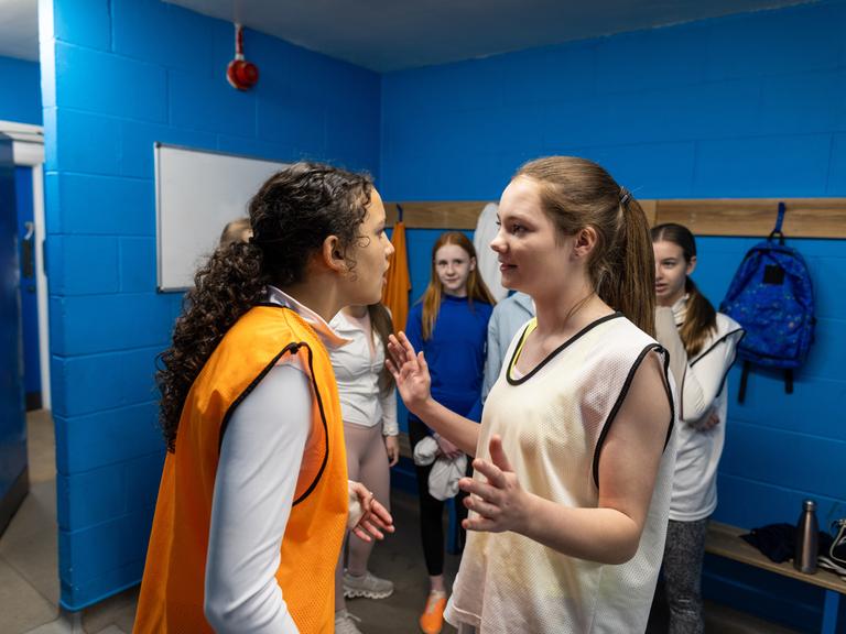 Konfliktlotsin: Mädchen in einer Schulumgebung neben Lockern, es sieht so aus, als hätte es einen Streit gegeben, ein Mädchen versucht, zu schlichten