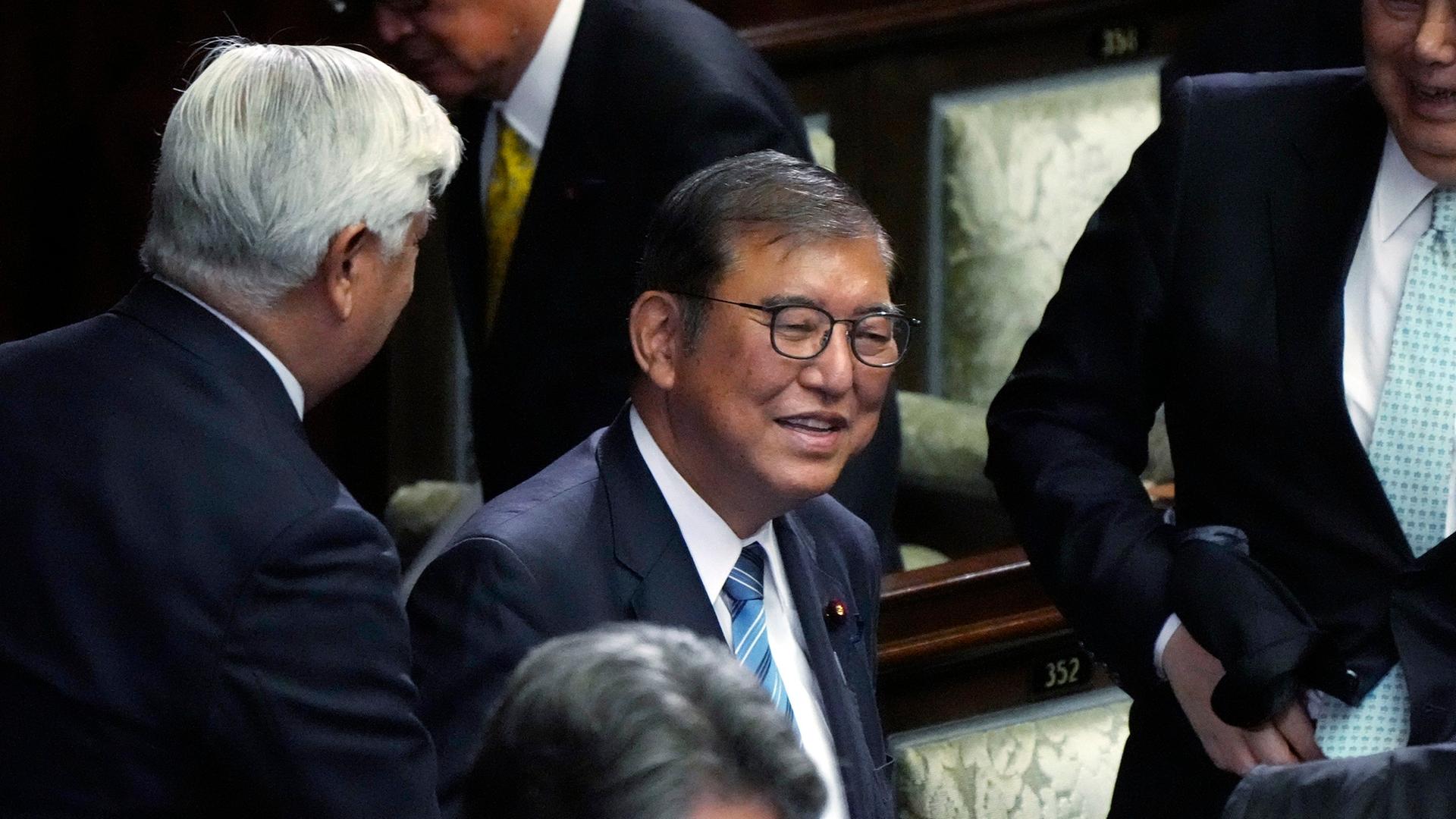 Der alte und neue japanische Premierminister Ishiba steht zwischen anderen Parlamentarieren und freut sich über Gratulationen. Der alte und neue japanische Premierminister Ishiba steht zwischen anderen Parlamentarieren und freut sich über Gratulationen.