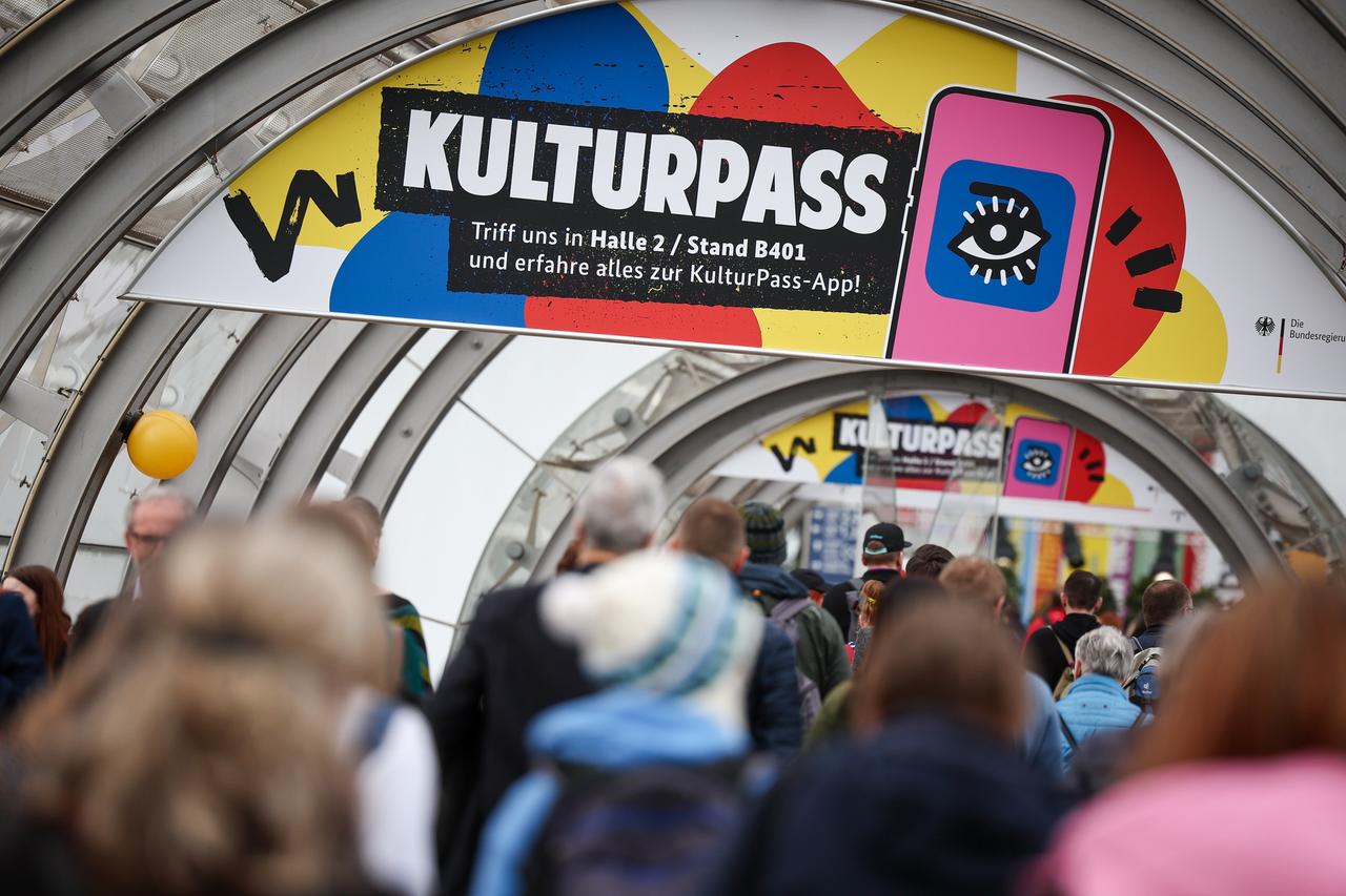 Besucher gehen unter einer Werbung für den Kulturpass über die Leipziger Buchmesse.