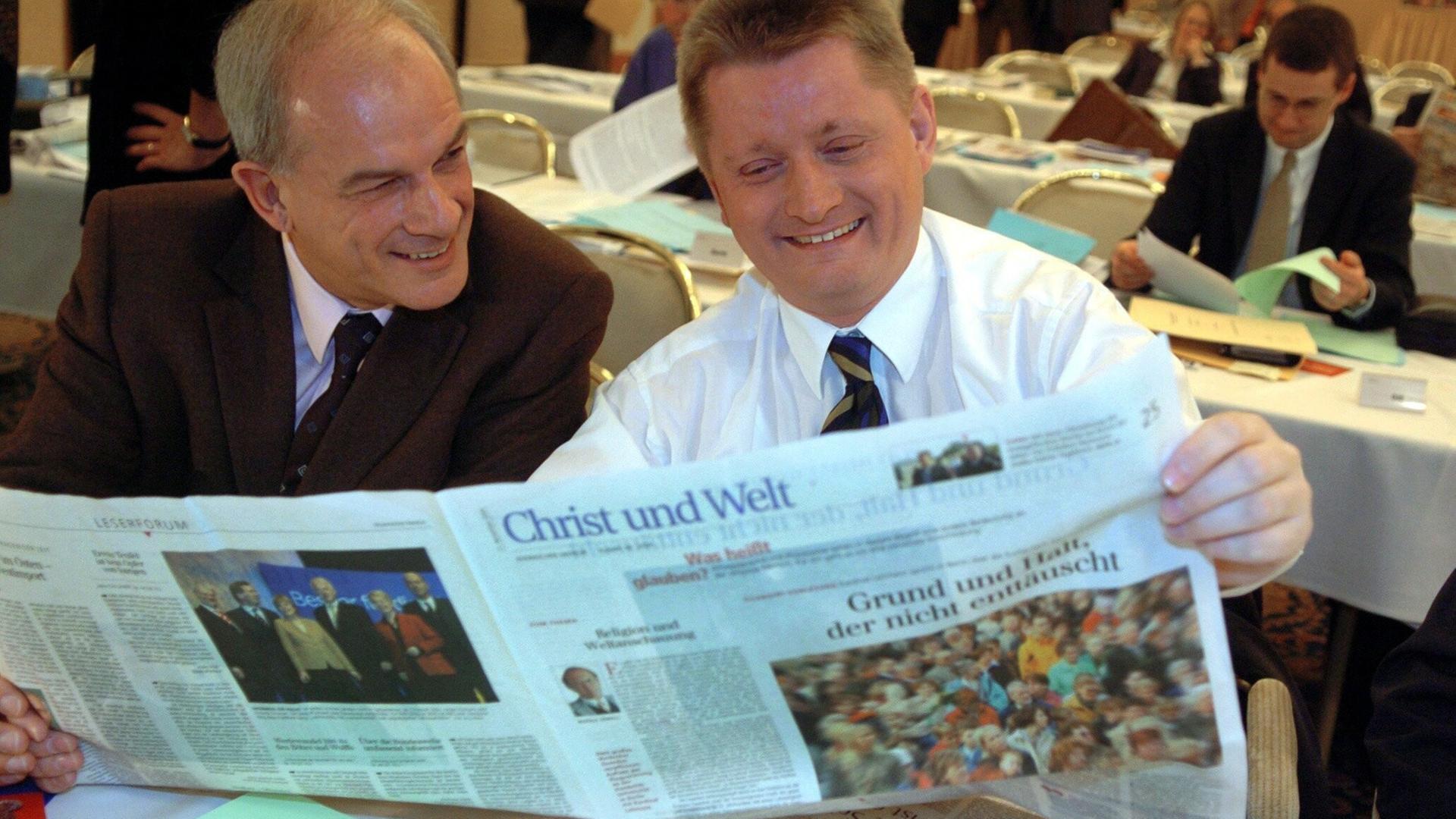 Zwei Männer sitzen an einem Tisch und bleick gemeinsam in eine aufgeschlagene Tageszeitung. Es handelt sich um die Zeitung "Christ und Welt". Das Foto stamm aus dem Jahr 2004. Zwei Männer sitzen an einem Tisch und bleick gemeinsam in eine aufgeschlagene Tageszeitung. Es handelt sich um die Zeitung "Christ und Welt". Das Foto stamm aus dem Jahr 2004.