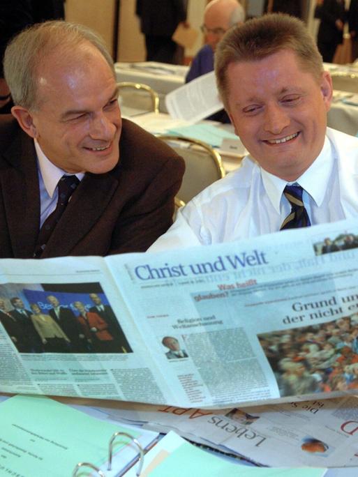 Zwei Männer sitzen an einem Tisch und bleick gemeinsam in eine aufgeschlagene Tageszeitung. Es handelt sich um die Zeitung "Christ und Welt". Das Foto stamm aus dem Jahr 2004. Zwei Männer sitzen an einem Tisch und bleick gemeinsam in eine aufgeschlagene Tageszeitung. Es handelt sich um die Zeitung "Christ und Welt". Das Foto stamm aus dem Jahr 2004.