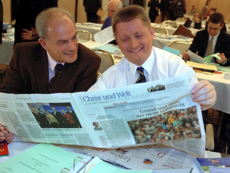 Zwei Männer sitzen an einem Tisch und bleick gemeinsam in eine aufgeschlagene Tageszeitung. Es handelt sich um die Zeitung "Christ und Welt". Das Foto stamm aus dem Jahr 2004. Zwei Männer sitzen an einem Tisch und bleick gemeinsam in eine aufgeschlagene Tageszeitung. Es handelt sich um die Zeitung "Christ und Welt". Das Foto stamm aus dem Jahr 2004.