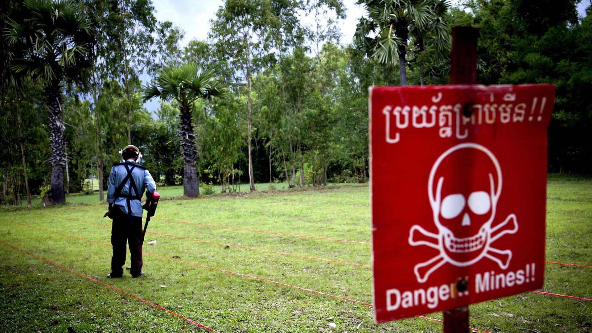 Eine Person sucht mit einem Metalldetektor nach Landminen in Kambodscha. 