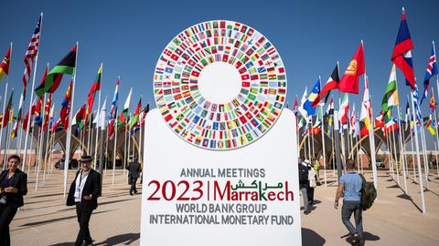 Bei der Jahrestagung des Internationalen Währungsfonds und der Weltbank steht ein Aufsteller vor dem Haupteingang mit der Aufschrift "Annual Meetings 2023 Marrakech - World Bank Group - International Monetary Fund".
