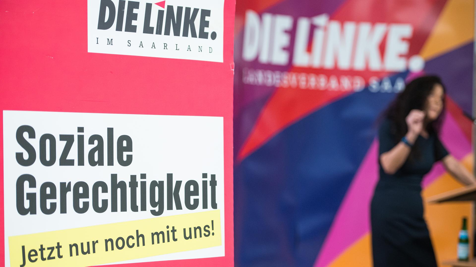 Ein Aufsteller des Landesverbandes von Die Linke Saar mit dem Slogan "Soziale Gerechtigkeit" steht bei der Mitgliederversammlung neben dem Podium. Im Hintergrund spricht Barbara Spaniol, die zur Spitzenkandidatin für die kommenden Landtagswahl im Saarland gewählt wurde. Ein Aufsteller des Landesverbandes von Die Linke Saar mit dem Slogan "Soziale Gerechtigkeit" steht bei der Mitgliederversammlung neben dem Podium. Im Hintergrund spricht Barbara Spaniol, die zur Spitzenkandidatin für die kommenden Landtagswahl im Saarland gewählt wurde.