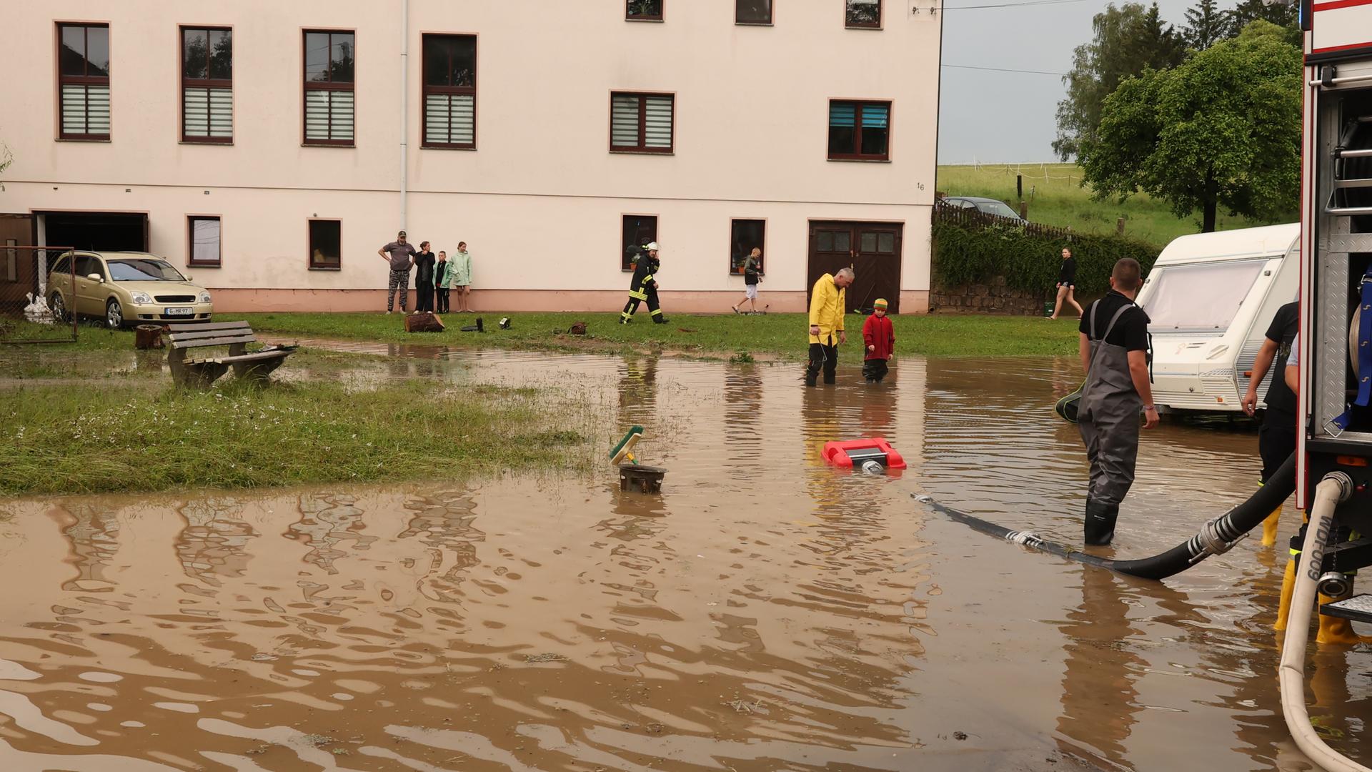 Nach einem Starkregen pumpen Einsatzkräfte der Feuerwehr auf einen Dorfplatz das Wasser ab. Nach einem Starkregen pumpen Einsatzkräfte der Feuerwehr auf einen Dorfplatz das Wasser ab.