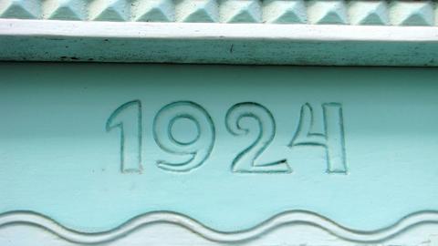 Eine mintgrüne Hausfassade zeigt die Jahreszahl 1924.