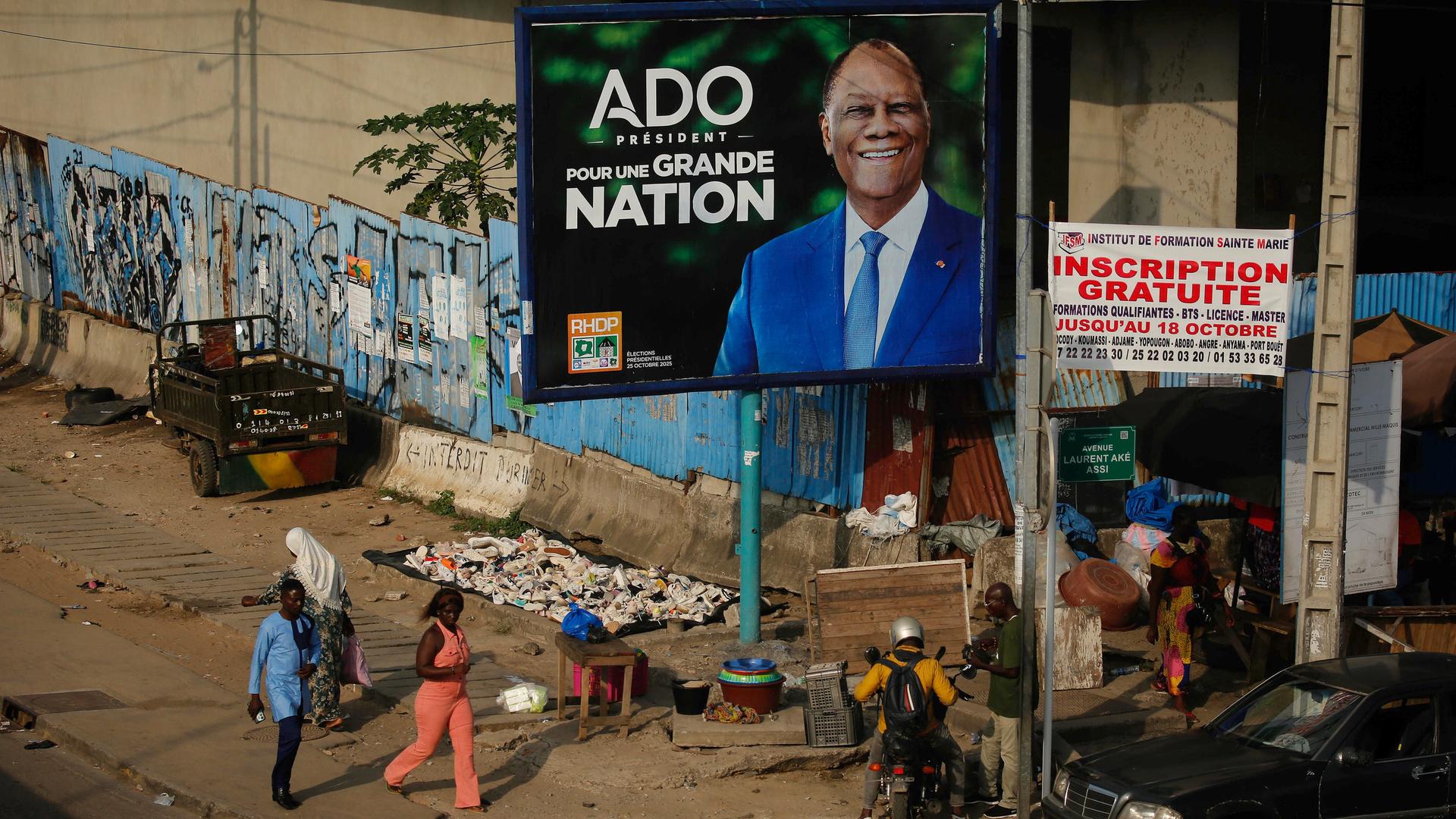 Menschen gehen an einer Wahlkampfanzeige des Präsidenten der Elfenbeinküste, Alassane Ouattara, vorbei. Die Elfenbeinküste wird am 25. Oktober 2025 Präsidentschaftswahlen abhalten. Menschen gehen an einer Wahlkampfanzeige des Präsidenten der Elfenbeinküste, Alassane Ouattara, vorbei. Die Elfenbeinküste wird am 25. Oktober 2025 Präsidentschaftswahlen abhalten.