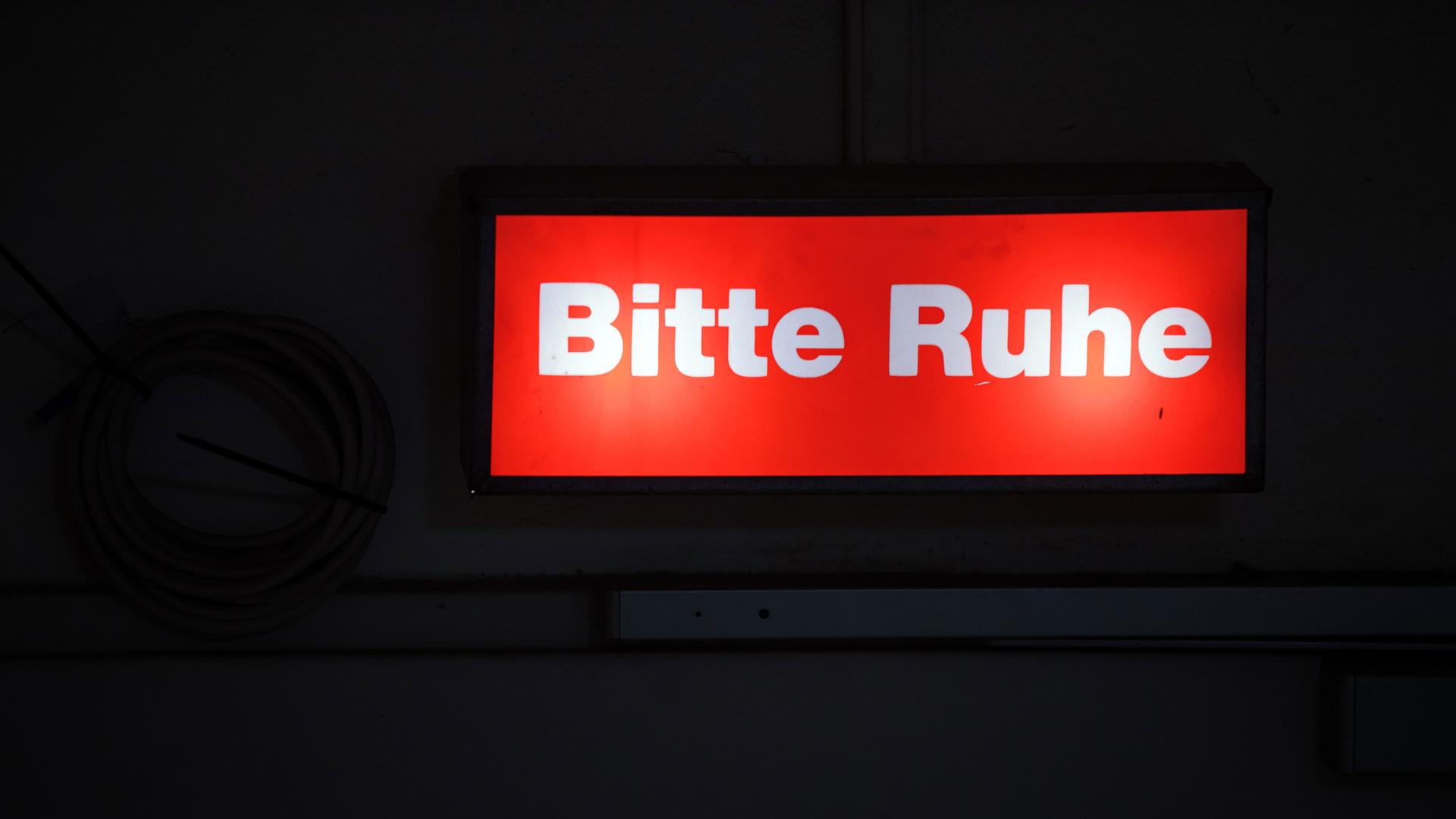 Ein Hinweisschild mit der Aufschrift "Bitte Ruhe" leuchtet am Bühnenzugang im Mecklenburgischen Staatstheater.