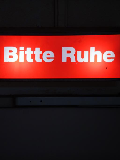 Ein Hinweisschild mit der Aufschrift "Bitte Ruhe" leuchtet am Bühnenzugang im Mecklenburgischen Staatstheater.