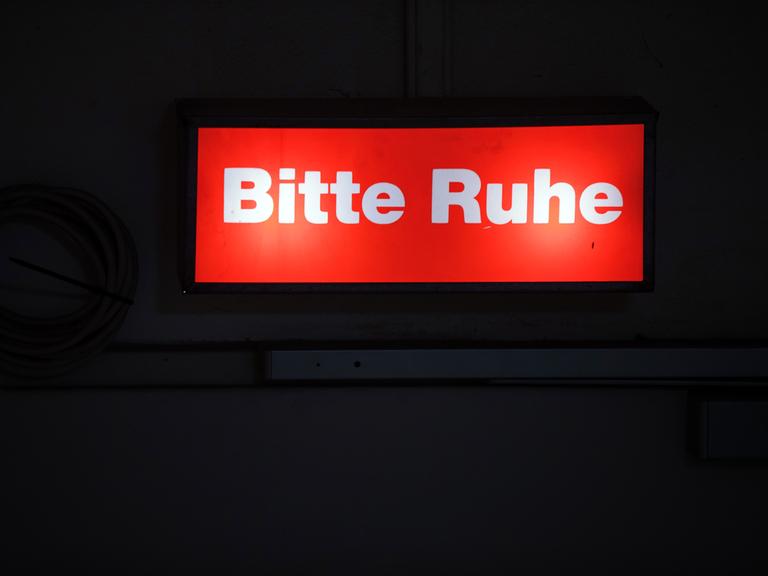 Ein Hinweisschild mit der Aufschrift "Bitte Ruhe" leuchtet am Bühnenzugang im Mecklenburgischen Staatstheater.