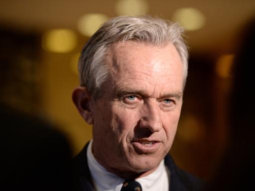 Portraitfoto von Robert F. Kennedy Jr. im Anzug vor dunklem Hintergrund