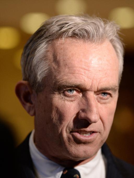 Portraitfoto von Robert F. Kennedy Jr. im Anzug vor dunklem Hintergrund