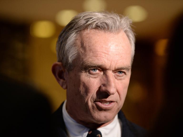 Portraitfoto von Robert F. Kennedy Jr. im Anzug vor dunklem Hintergrund