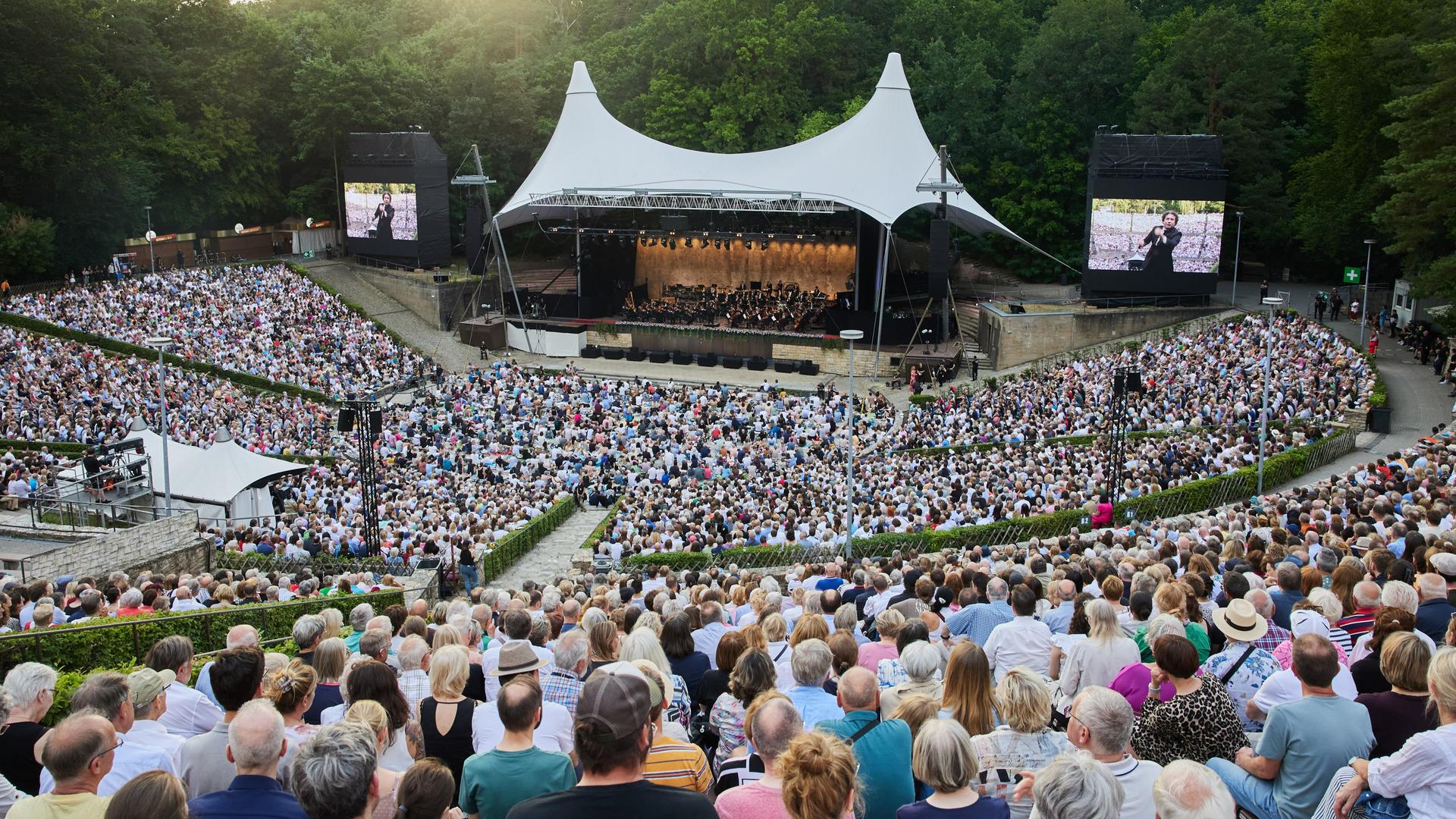 Hunderte Zuschauer hören ein Konzert openair in der Berliner Waldbühne, auf dem Podium spielt ein Orchester.