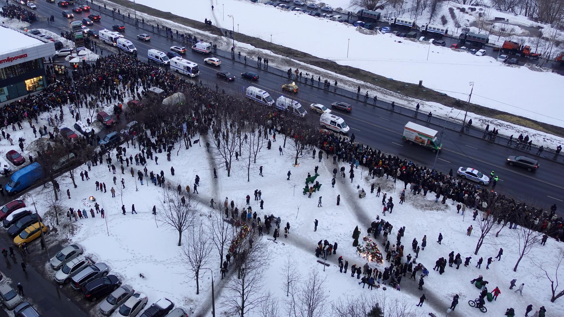 Blick aus großer Höhe auf die Menschen, die am Rande einer Straße und auf einer schneebedeckten Fläche Schlange stehen. Blick aus großer Höhe auf die Menschen, die am Rande einer Straße und auf einer schneebedeckten Fläche Schlange stehen.