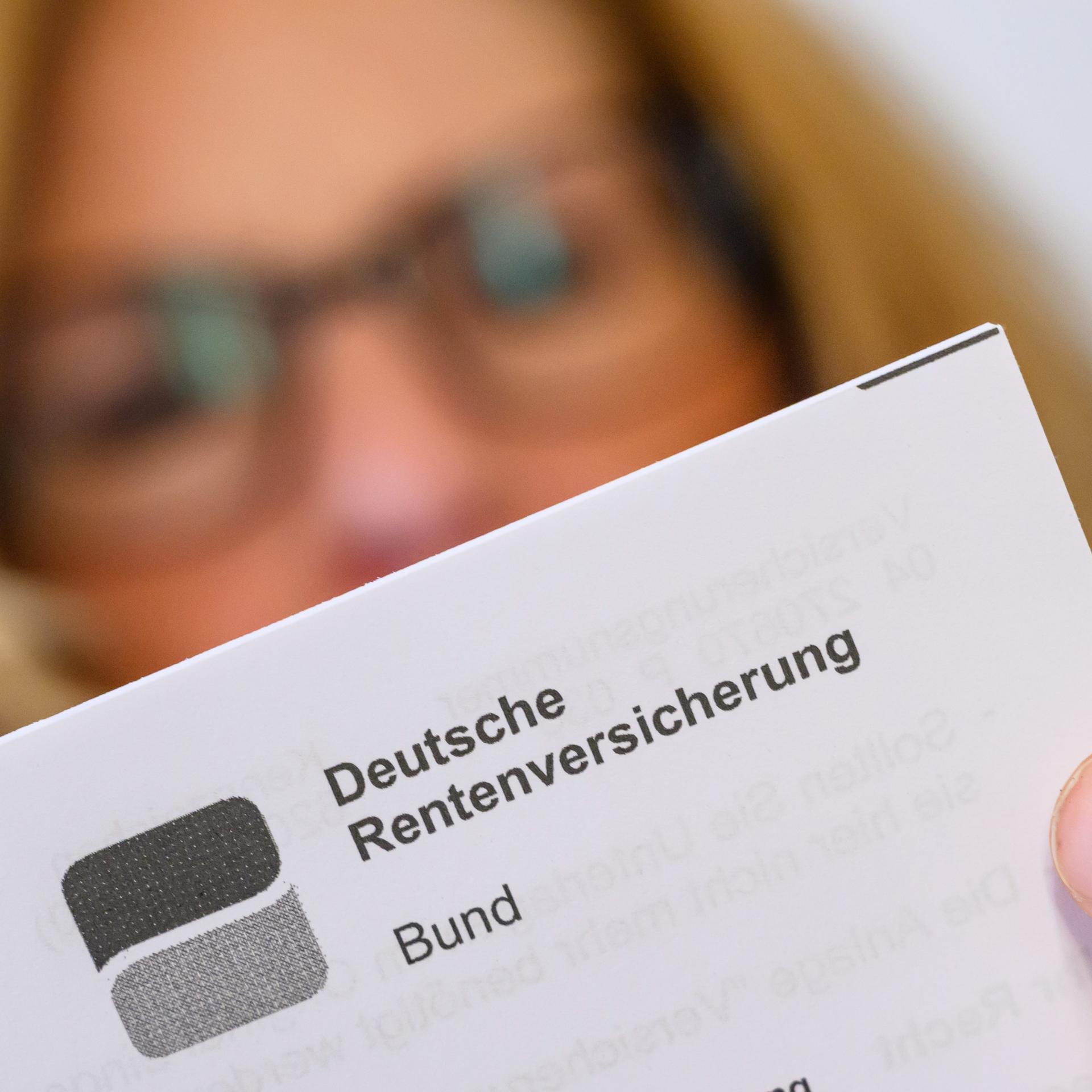 Eine Frau liest ein Schreiben der Deutschen Rentenversicherung in ihrer Wohnung. 