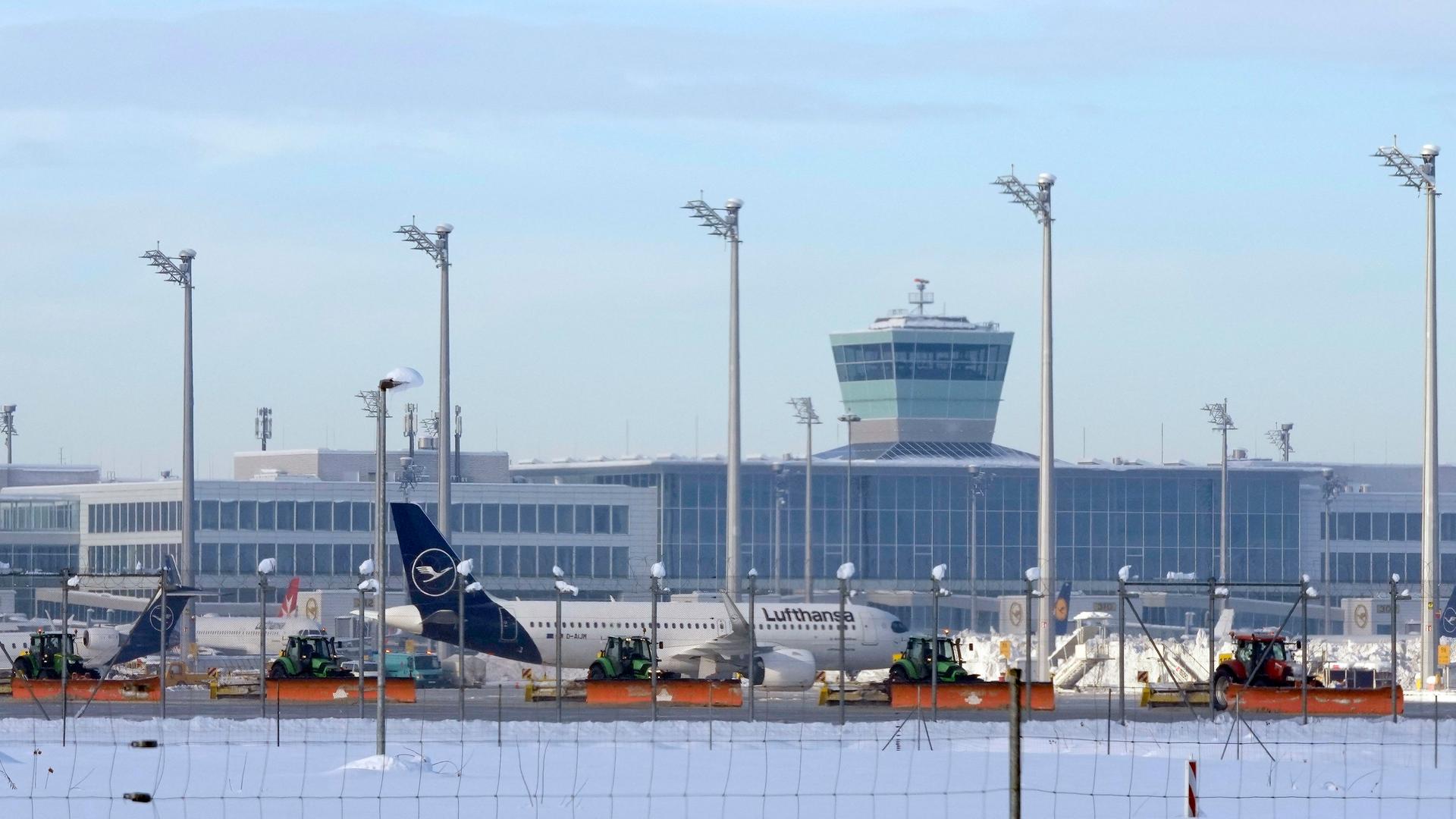 Bayern, München: Flughafenmitarbeiter räumen Schnee und Eis vom Vorfeld zwischen den Flugzeugen.