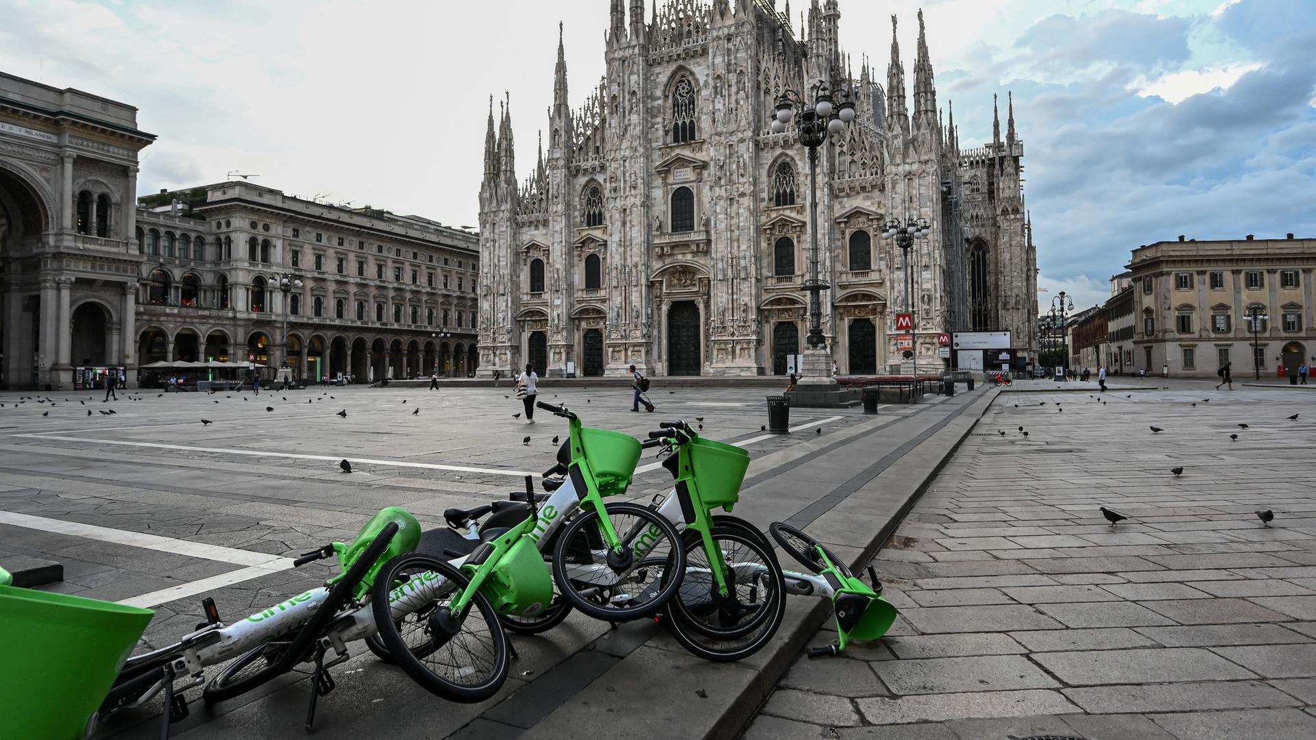 Ein Blick auf die leere Piazza Duomo in Mailand nach einem schweren Regensturm. Fahrräder mit Anhängern liegen umgekippt auf dem Weg. Ein Blick auf die leere Piazza Duomo in Mailand nach einem schweren Regensturm. Fahrräder mit Anhängern liegen umgekippt auf dem Weg.