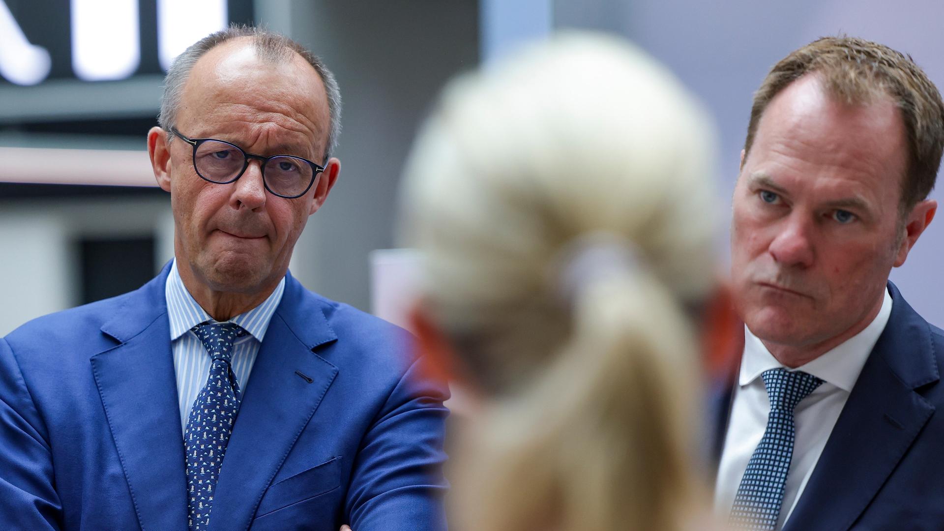 Kanzler und CDU-Chef Friedrich Merz (links) mit Düsseldorfs Oberbürgermeister Stefan Keller (CDU) in der Firma Henkel. Vor ihnen steht von hinten zu sehen eine blonde Frau