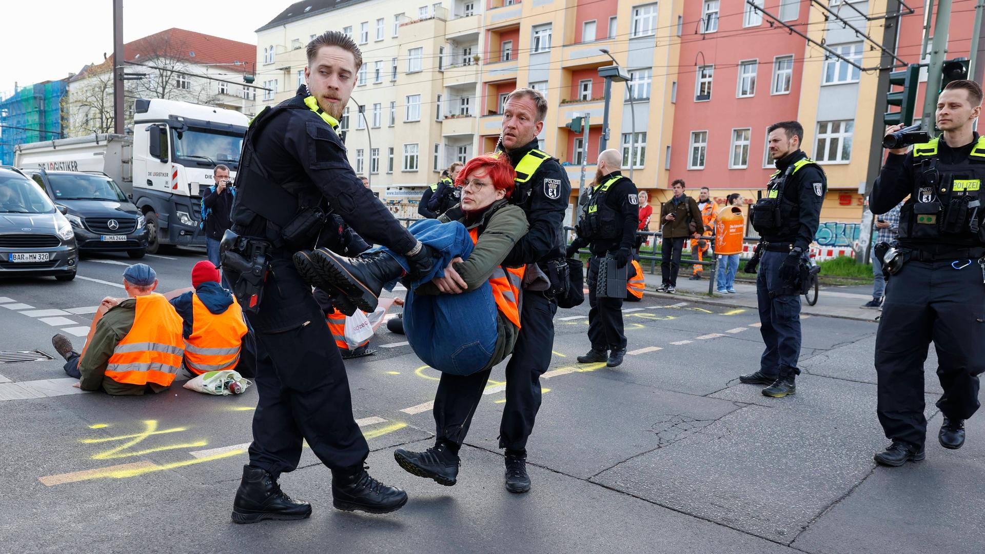 Polizisten tragen am 24.04.2023 eine Aktivistin der Letzen Generation von der Strassenblockade in Berlin.